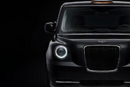 Front view of a black SUV with a prominent chrome grille and halo LED headlight against a dark background, highlighting its premium design.